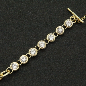 Detail of gold crystal bracelet with toggle clasp on black textured background