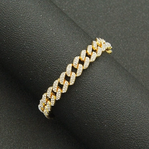 Close-up of hip hop gold Cuban link bracelet with iced out crystals on black display