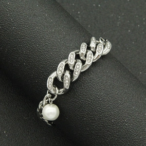 Silver Cuban link bracelet with pavé rhinestones and a pearl pendant on a black stand