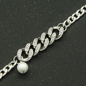 Cuban chain bracelet with pavé rhinestones and white pearl charm on black background