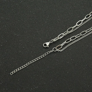 Detail view of silver layered paperclip chain with lobster clasp on a dark background
