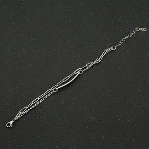 Detail of layered stainless steel bracelet with mixed chains and a goodluck metal bar
