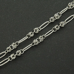 Detail of silver link chain necklace featuring a minimalist industrial design on a black texture