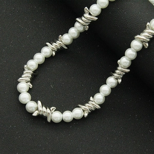 Collier style punk avec perles blanches et épines en métal argenté sur fond noir
