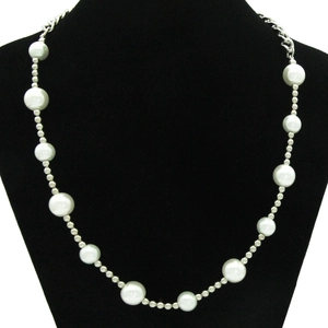 Détail d'un collier de mode avec perles blanches et billes argentées sur un buste noir