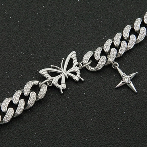 Gourmette cubaine argentée sertie avec pendentifs papillon et étoile sur fond noir