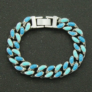 Détail d'une chaîne cubaine argentée avec incrustations d'émail bleu et cyan sur noir
