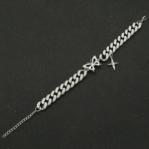 Détail du bracelet chaîne cubaine argentée avec breloque papillon et pendentif étoile