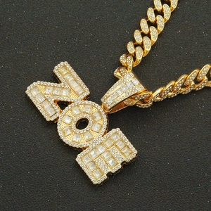 Macro view of gold iced out YOI letter pendant with crystal encrusted Cuban chain link