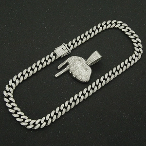 Détail d'une chaîne cubaine glacée et d'un pendentif signe de main en argent avec strass