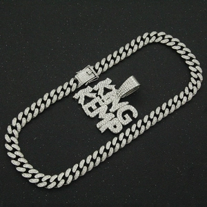 Detailed view of silver iced-out KING KEMP letter pendant on a rhinestone Cuban link chain