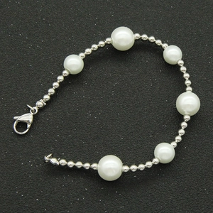 Vue macro détaillée de perles blanches et de perles argentées polies sur le bracelet à fermoir