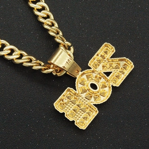 Macro shot of gold Cuban chain and FOX pendant with textured geometric studs