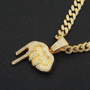 Gros plan sur un collier cubain doré avec pendentif geste rock et strass brillants