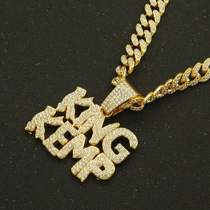 Macro shot of iced out gold KING pendant and cubic zirconia studded Cuban link chain