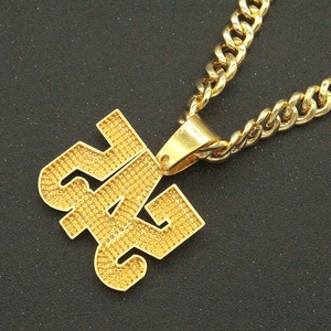 Macro view of gold-plated GANG pendant necklace with full iced-out texture and Cuban chain