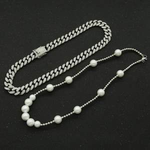 Détail du collier chaîne cubaine à cristaux et collier de perles sur fond noir élégant