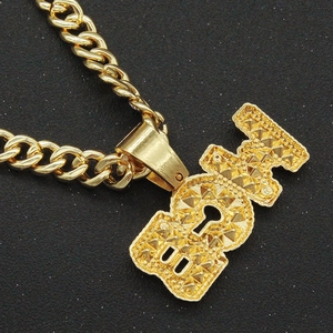 Detalle de la cadena cubana dorada con colgante de letras BOY y acabado con textura