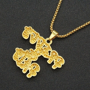 Détail du pendentif V12 doré avec texture granuleuse sur une chaîne à mailles