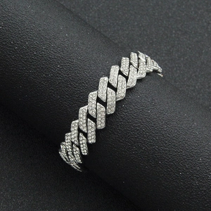 Gros plan du bracelet gourmette argenté 13mm serti de diamants sur un support noir mat