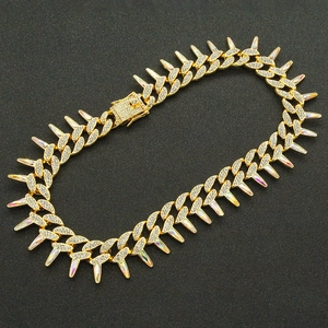 Macro shot of gold Cuban link chain with colorful iridescent spikes and zircon accents