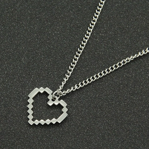 Gros plan détaillé d'un collier avec pendentif cœur pixelisé en argent et texture métallique