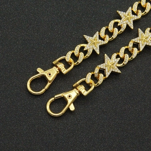 Detail of gold Cuban chain pants accessory with rhinestone-encrusted star charms