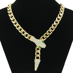 Gros plan d'un collier chaîne cubaine serpent doré orné de strass et de pierres vertes