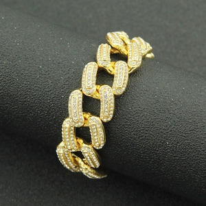 Vue macro d'un bracelet maille cubaine dorée avec zircons étincelants style hip-hop urbain
