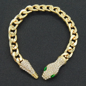 Macro detail of golden Cuban link snake bracelet with sparkling crystals and green eyes