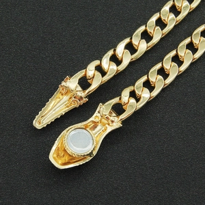 Polished gold curb chain bracelet with magnetic clasp on a textured black surface