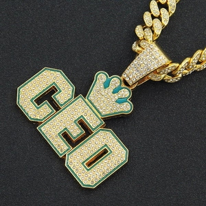 Détail du collier chaîne cubaine dorée avec pendentif couronne CEO et émail vert