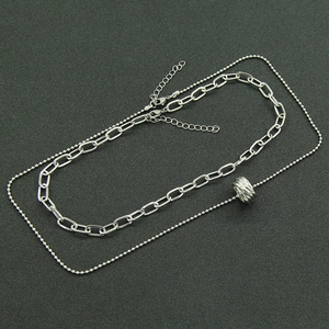 Double-layered silver link chain necklace with bead strand and textured cylinder pendant