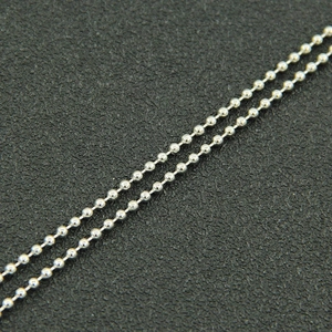 Macro detail of glossy silver ball chain with minimalist dual-layer beaded design