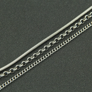 Macro detail of silver stainless steel snake, rolo, and cross chains for necklaces