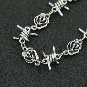 Detailed close-up of retro silver necklace with rose and barbed wire gothic elements