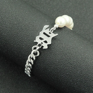 Cuban chain and pearl bracelet featuring a Gothic letter B charm on black stand