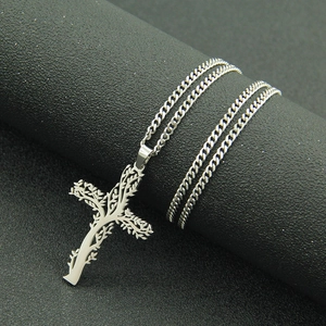 Détail macro du pendentif croix arbre de vie argenté sur une chaîne gourmette élégante
