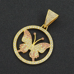 Macro view of iced out butterfly circle pendant with pink zircons and gold plating