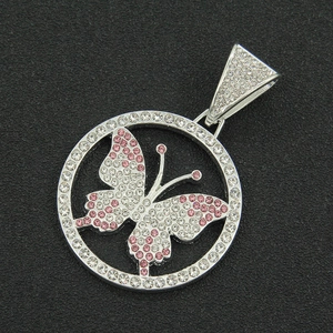 Macro shot of iced out silver butterfly pendant with pink and white stones in a circular frame