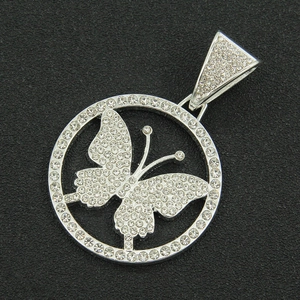 Close-up of iced out hollow butterfly pendant with white crystals on a black texture