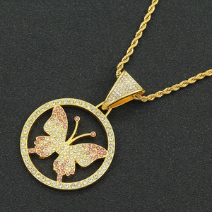 Macro shot of gold hip hop pendant with pink crystals and butterfly detail on rope chain