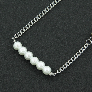 Detailed view of six white pearls arranged horizontally on a minimalist silver chain