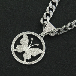Close-up of iced out butterfly pendant on a silver Cuban link chain with crystals