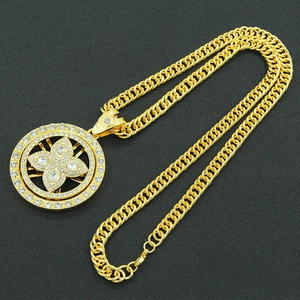 Détail d'un pendentif hip-hop doré rotatif serti de cristaux sur une grosse chaîne cubaine