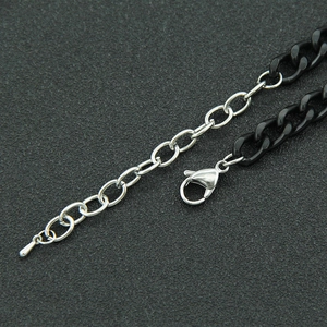 Detail van de tweekleurige Cubaanse ketting met zilveren karabijnsluiting en zwarte schakels