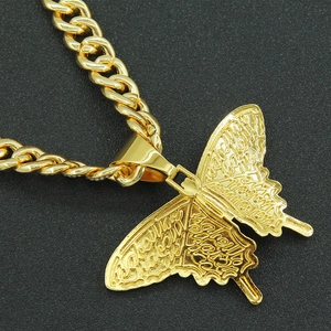 Gros plan d'une chaîne cubaine dorée avec pendentif papillon détaillé et gravure d'ailes