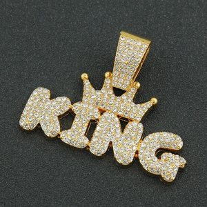 Detailed view of iced-out gold King pendant with sparkling rhinestones on textured background