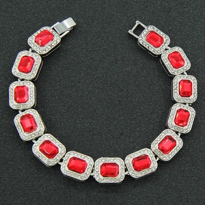 Macro detail of silver hip-hop bracelet featuring rectangular red stones and pavé diamonds