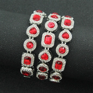 Detailaufnahme von drei silbernen Panzerarmbändern mit roten Diamanten auf Ständer